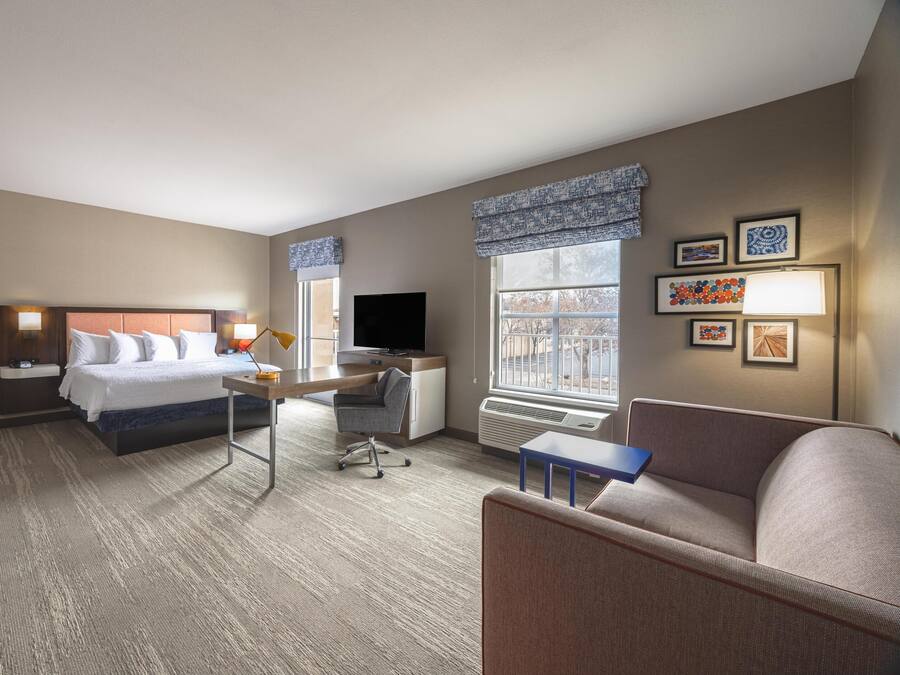 Una habitación de hotel con cama, escritorio, silla y sofá.