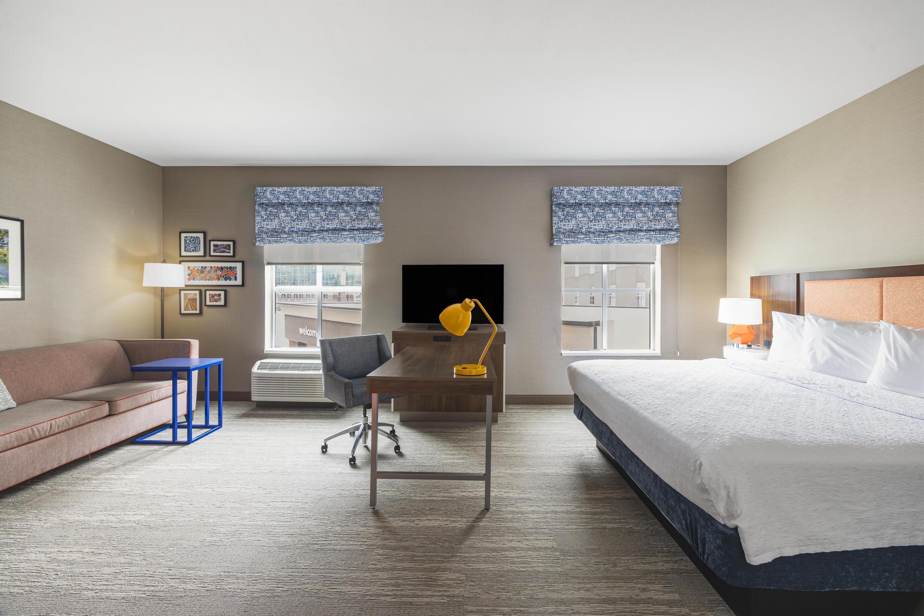 Een hotelkamer met een bed, een bureau, een stoel, een bank en een televisie.