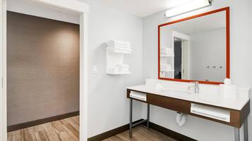 A modern bathroom with a white sink, a large mirror with a red frame, and a towel rack.