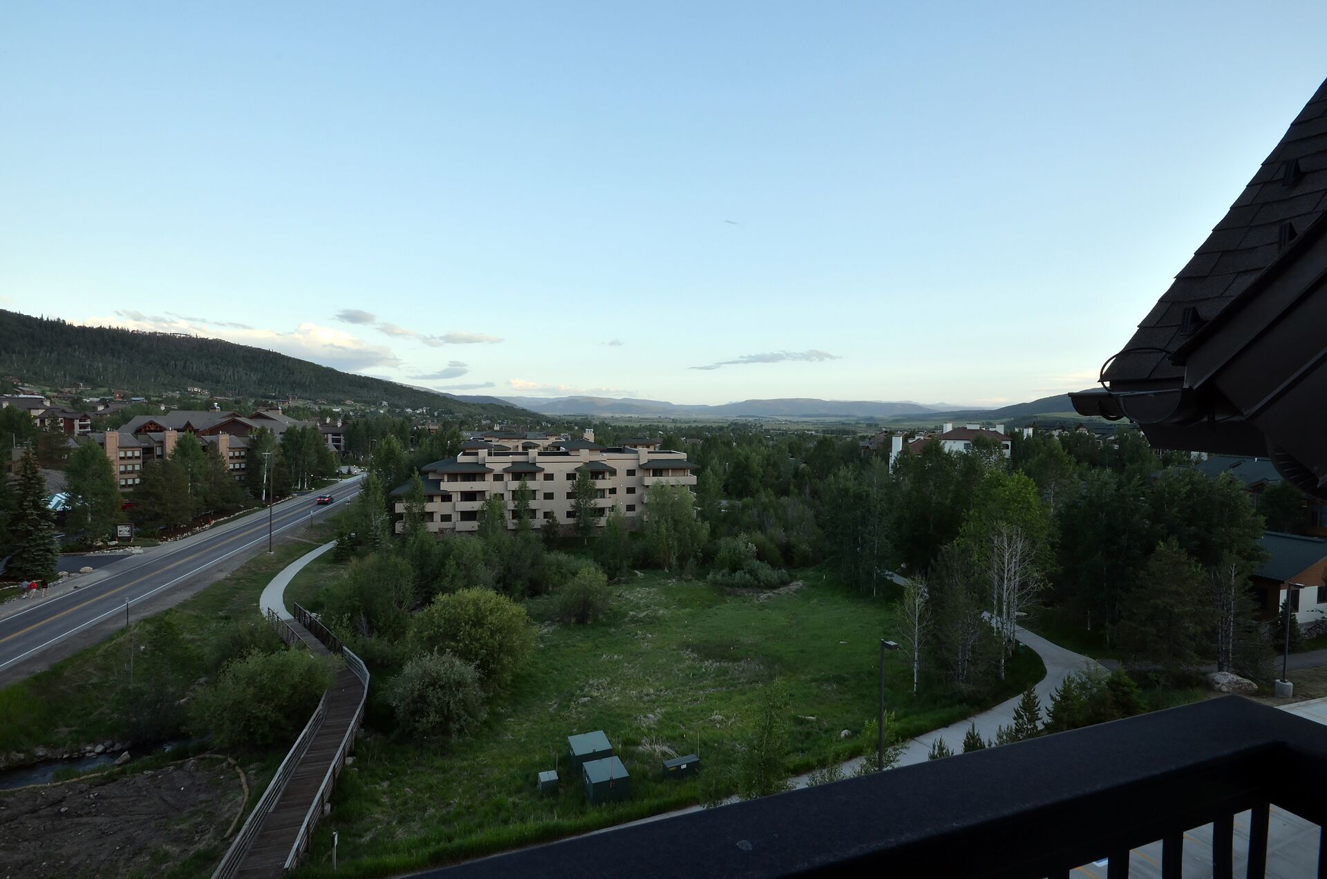 Vue d’un quartier résidentiel avec un grand immeuble, une route et de la végétation environnante.