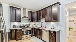 A modern kitchen with dark wood cabinets, stainless steel appliances, and a white tiled backsplash.