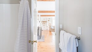 A bathroom with a white shower curtain, a towel rack, and a visible door handle. - Chatham walk to Cape Cod beach  (Chatham)