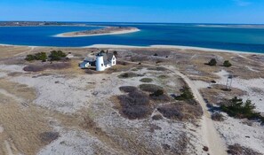 A white lighthouse on a sandy beach with a clear view of the ocean. - Chatham walk to Cape Cod beach (Chatham)