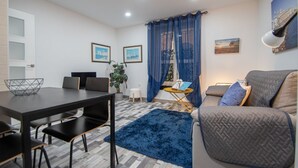 Ein modernes Wohnzimmer mit Esstisch, einer Couch und einem blauen Teppich.