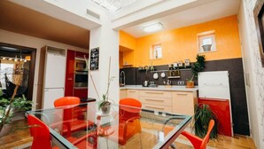 Eine moderne Küche mit orangefarbenen und schwarzen Wänden, einem Glastisch mit roten Stühlen sowie einem weißen Kühlschrank.