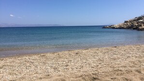 A pebble beach with clear blue water and rocky outcrops. - Idyllic Views one-bedroom apartment in quite and relaxing Tripiti  (Paros)