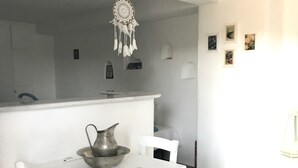 A white dining table with chairs, a dreamcatcher, and a pitcher on the table. - Idyllic Views one-bedroom apartment in quite and relaxing Tripiti  (Paros)