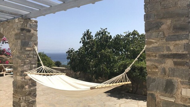 A hammock under a white pergola, set against a stone wall with a view of the sea. - Idyllic Views one-bedroom apartment in quite and relaxing Tripiti  (Paros)
