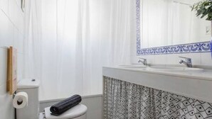 Ein Badezimmer mit Toilette, Waschbecken und einem Spiegel mit blauem Rahmen.
