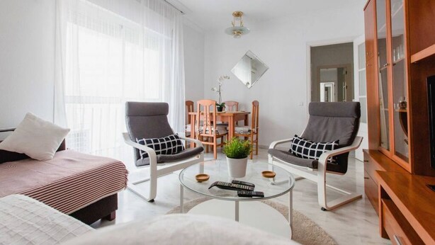 Ein modernes Wohnzimmer mit einer Couch, zwei Sesseln, einem Couchtisch und einer TV-Konsole.