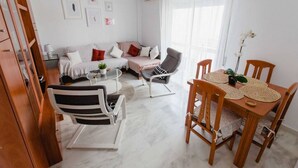 Ein modernes Wohnzimmer mit einer Couch, Sesseln, einem Esstisch und einer Treppe.