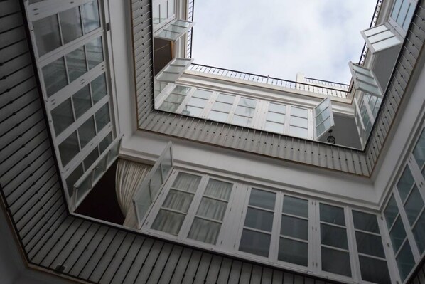 Sicht aus der Ecke eines Zimmers mit Oberlicht, Fenster und Balkon mit Geländer.