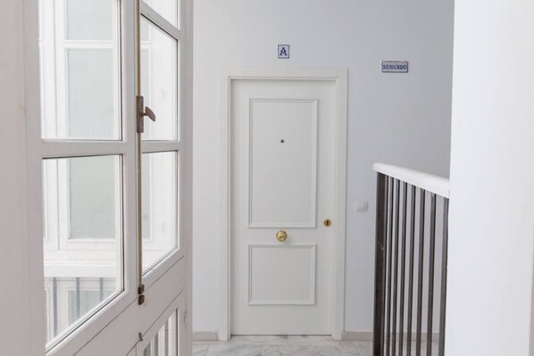 A white door with a brass doorknob, a small sign above it, and a metal railing to the right.