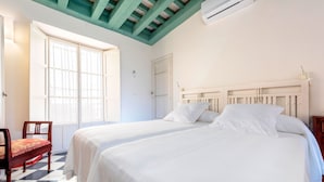 Een kamer met twee bedden, een stoel, een raam en een plafond met zichtbare balken.