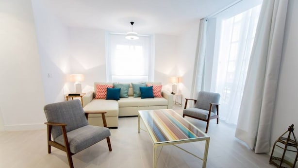 Un salon moderne comprenant un canapé, deux fauteuils, une table basse et un ventilateur de plafond.