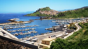 A coastal marina with numerous boats docked, a prominent hilltop fort, and a clear view of the sea. - Affittimoderni Castelsardo The Miramare (Castelsardo)