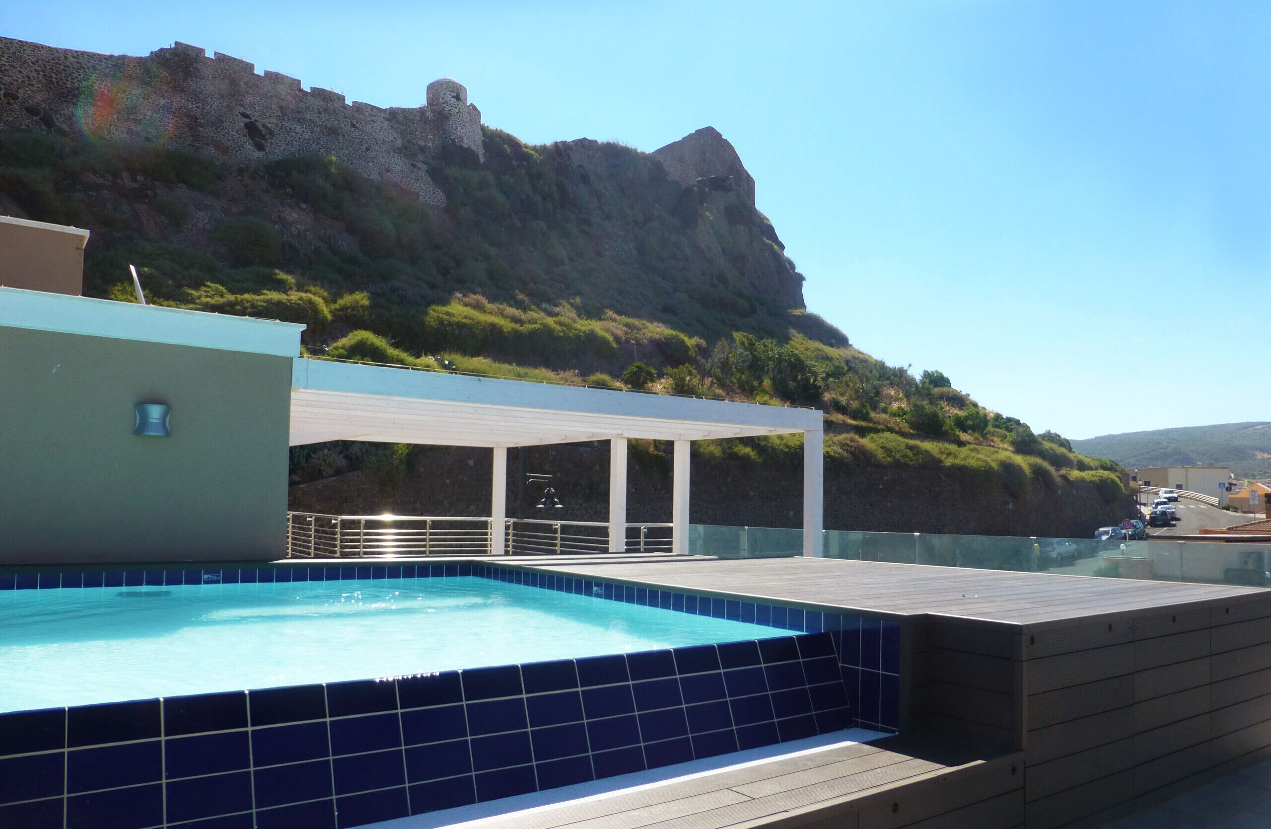 Una piscina en la azotea con vista a una colina rocosa y un cielo despejado.
