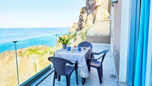A balcony with a table and chairs overlooking a cliff and the sea. - Affittimoderni Castelsardo The Miramare (Castelsardo)