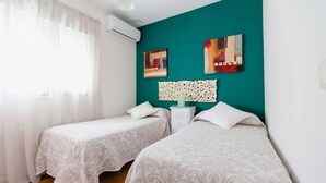 Un dormitorio con dos camas, una pared de acento color turquesa y obras de arte.