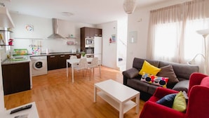 Un apartamento moderno con cocina, comedor y sala de estar. Cuenta con un sofá, una mesa de centro y una mesa de comedor con sillas.