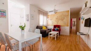 Una sala moderna con comedor, un sofá, un sillón rojo y un mapa mundial en la pared.