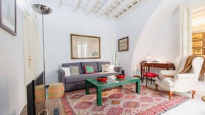 A living room with a sofa, a coffee table, a chair, a TV, and a patterned rug. - Duplex de la Botanica - Cadiz (Cádiz)