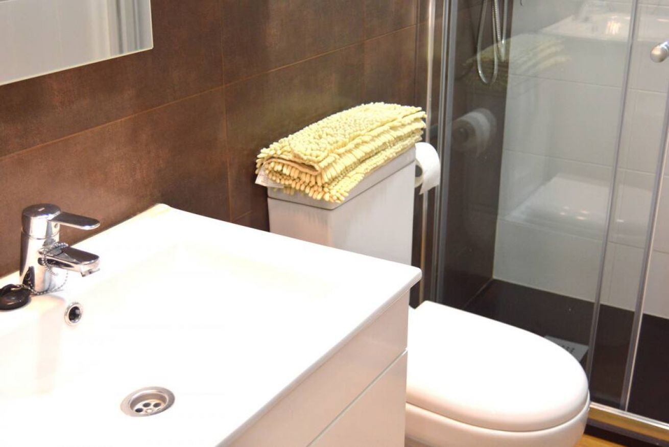 A bathroom with a white sink, a toilet, and a glass shower enclosure.