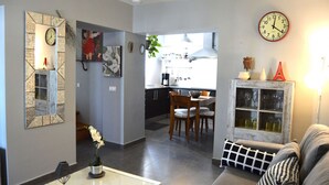 A modern living room with a sofa, a coffee table, and a dining area with a table and chairs. There is a kitchen visible in the background with a clock on the wall. - El Mirador de Cádiz (C��diz)