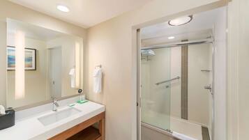 A modern bathroom with a large mirror, two sinks, and a glass-enclosed shower.