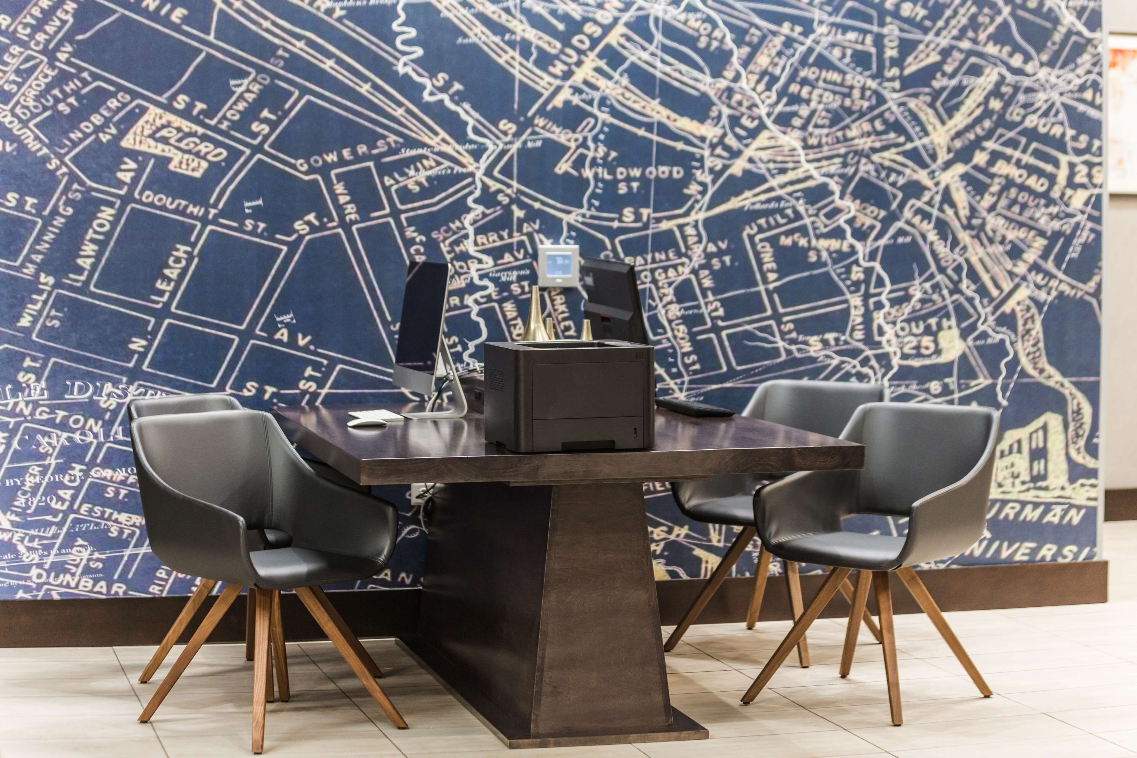 A conference room with a map-themed wall, a dark wooden table, and four modern chairs.