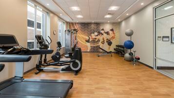 A gym with treadmills, elliptical machines, and exercise balls.
