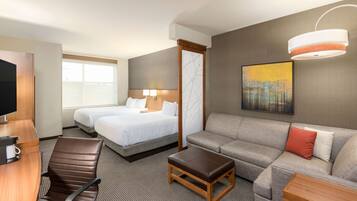 A hotel room with a bed, a sofa, a desk, and a TV.