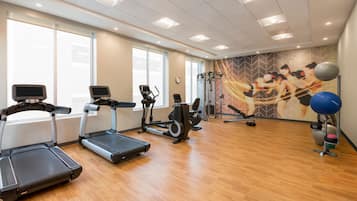 A gym with treadmills, elliptical machines, and exercise balls.