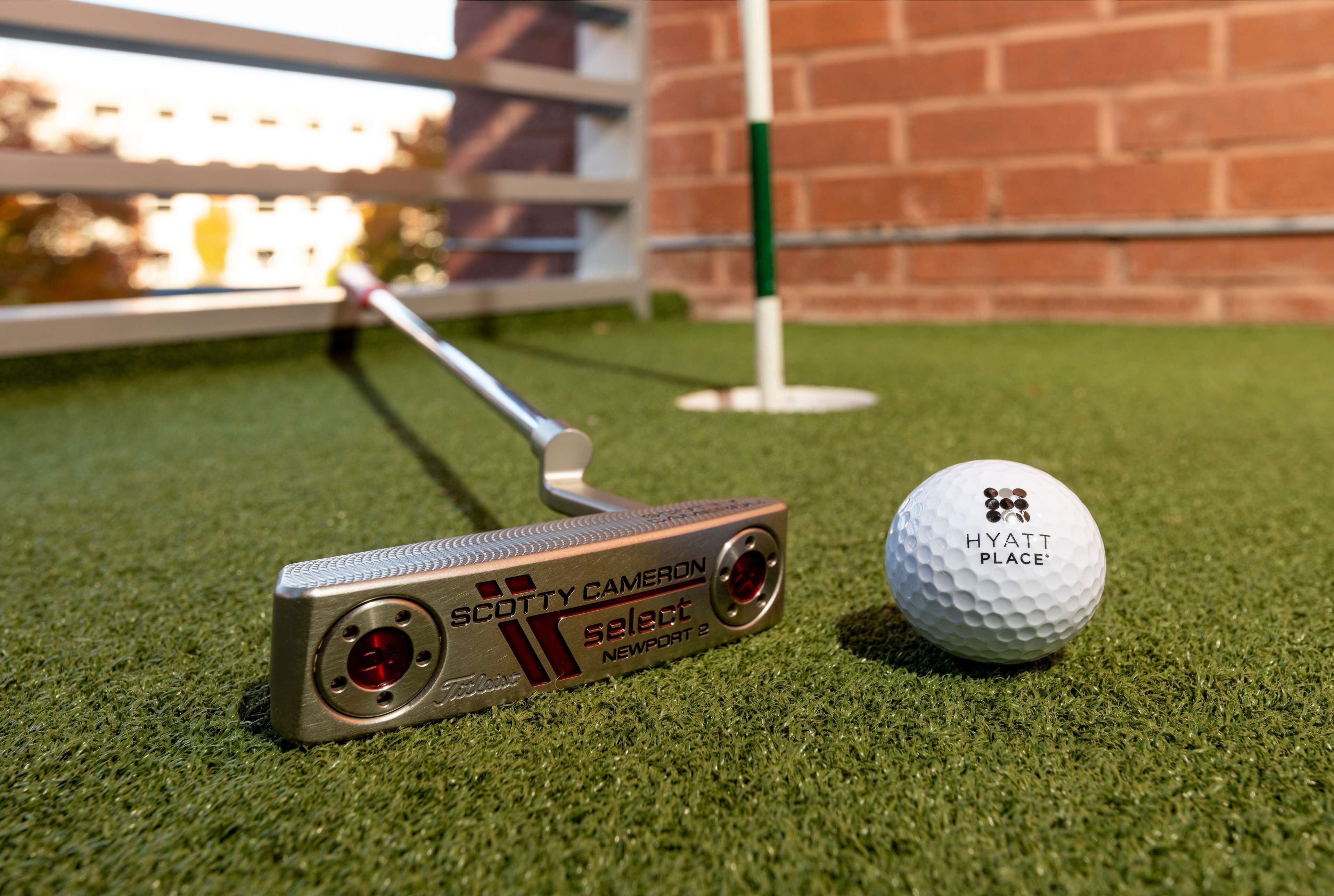 A putter and a golf ball on artificial turf.
