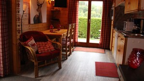 Ein gemütliches Blockhaus-Interieur mit Essbereich, Holzwänden, einem Fernseher und Blick auf Grünflächen.
