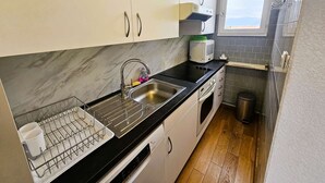 A compact kitchen with white cabinets, a black countertop, a built-in microwave, and a window providing natural light. - 2 rooms with Big terrace of 25m ² in 350M of the Beach (ST MANDRIER SUR MER)