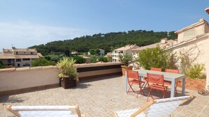 A rooftop terrace with a table and chairs, potted plants, and a view of a hillside with buildings. - 2 rooms with Big terrace of 25m ² in 350M of the Beach (ST MANDRIER SUR MER)