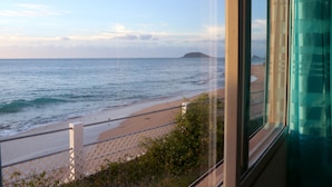 A coastal view from a window overlooking a beach with a fence and vegetation. - Escape with the sound of the waves (Deshaies)