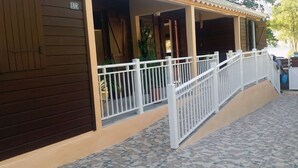 A building with a covered porch, a white railing, and a tiled floor. - Escape with the sound of the waves (Deshaies)