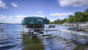 A floating dock with a covered seating area and a small boat. - Riesling Rod and Reel: Fishers Paradise (Honeoye)