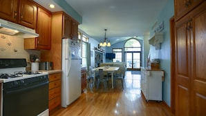 A kitchen with wooden cabinets, a stove, refrigerator, and a dining area with a table and chairs. - Riesling Rod and Reel: Fishers Paradise (Honeoye)