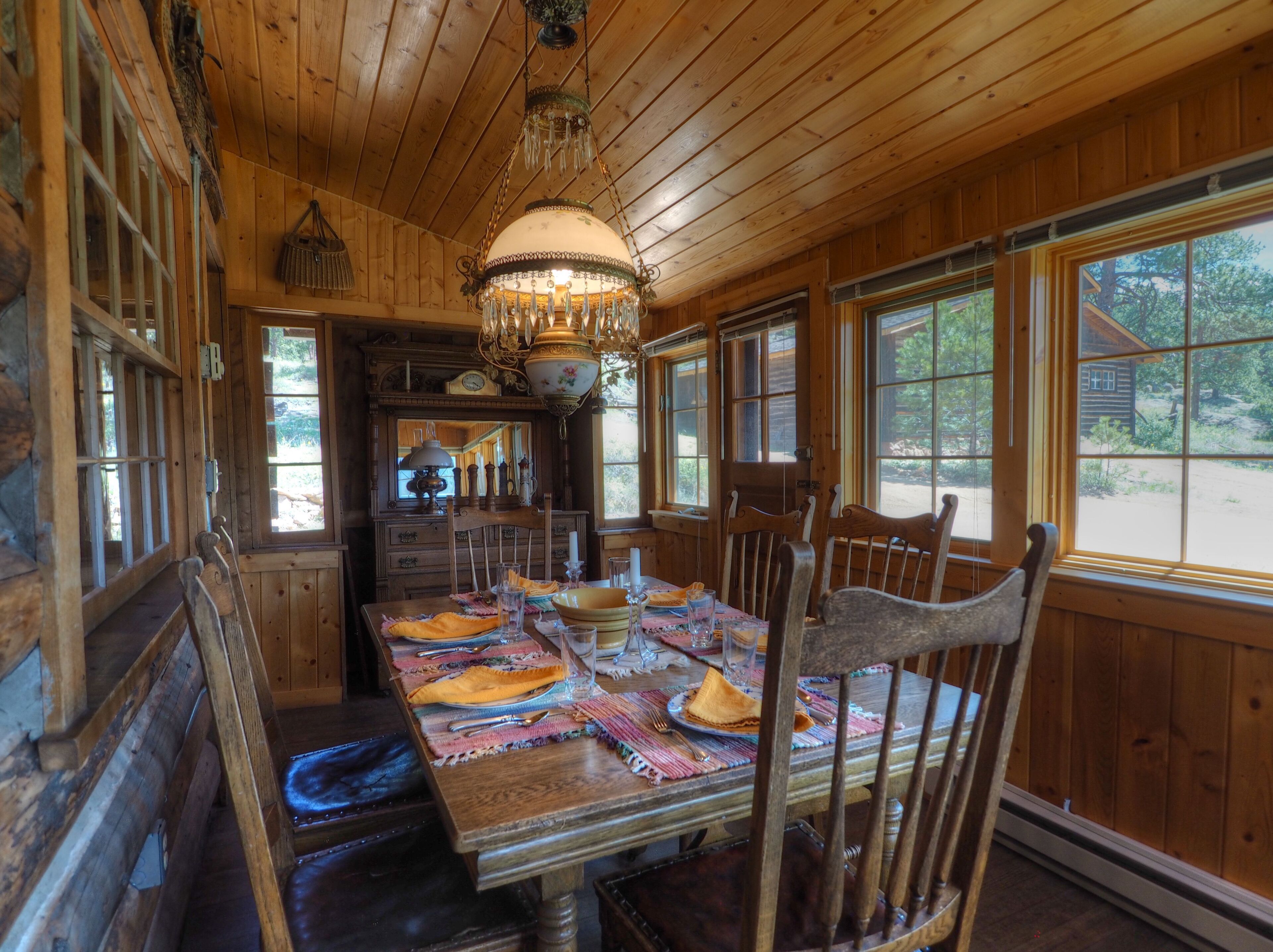 A wooden dining room with a large table set for a meal, wooden chairs, and a chandelier.