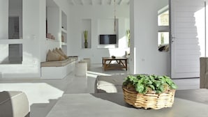 A modern, minimalist living room with a sofa, a coffee table, and a TV. - Aelya (Paros)