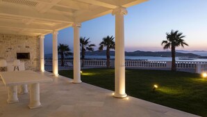 A covered outdoor area with stone walls, a table, and columns. - Aelya (Paros)