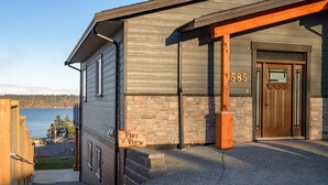 A modern building with a 'Pier View' sign, a wooden door, and the number 585. - Pier View Suite, Stunning Ocean View. (Campbell River)