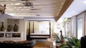 Une chambre à coucher moderne avec un lit à baldaquin, un coin salon avec un canapé et une table à manger.