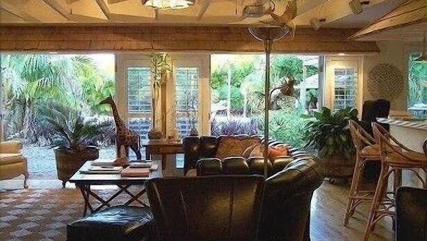 Un salon spacieux avec un canapé en cuir, une table à manger et diverses plantes en pot.