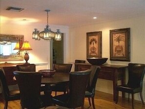 A dining area with a round table, chairs, a chandelier, and framed artwork on the wall. -  Private tropical paradise 155 5 ⭐️ reviews. No cleaning, pet fees. Clothing opt. (Ft Myers)