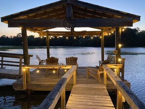 Un pontile in legno con sedie e luci decorative, affacciato su un'acqua calma.