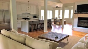 A spacious living room with a large sofa, a wooden coffee table, and a fireplace. - Shem Creek Paradise. Fish, Paddle, Kayak Off Your Own Covered dock with floater (Mt Pleasant)